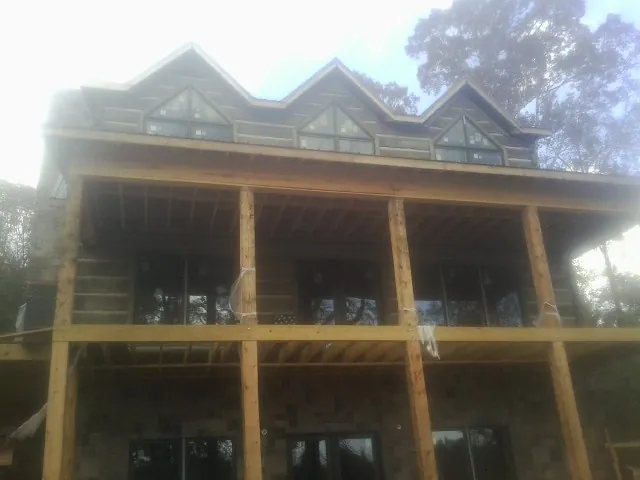 Dormers and porch framing on a large log home under construction — Roof Coating work by our crew in Sallisaw